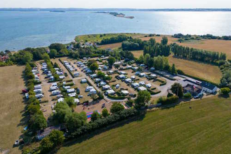 Omkranset af skov, beliggende skrånende mod havet med udsigt over Helnæsbugten - ligger vi