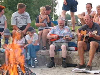 Lejrchefen selv (til højre) underholdt omkring bålet - og han blev fra tid til anden gæstet af besøgende, der havde medbragt egne instrumenter. Her en tysk turist med en ukulele.